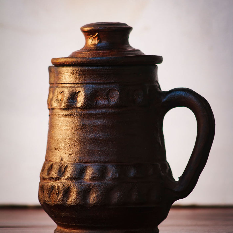 A handcrafted earthenware jug with a rich textured surface, shown close up.