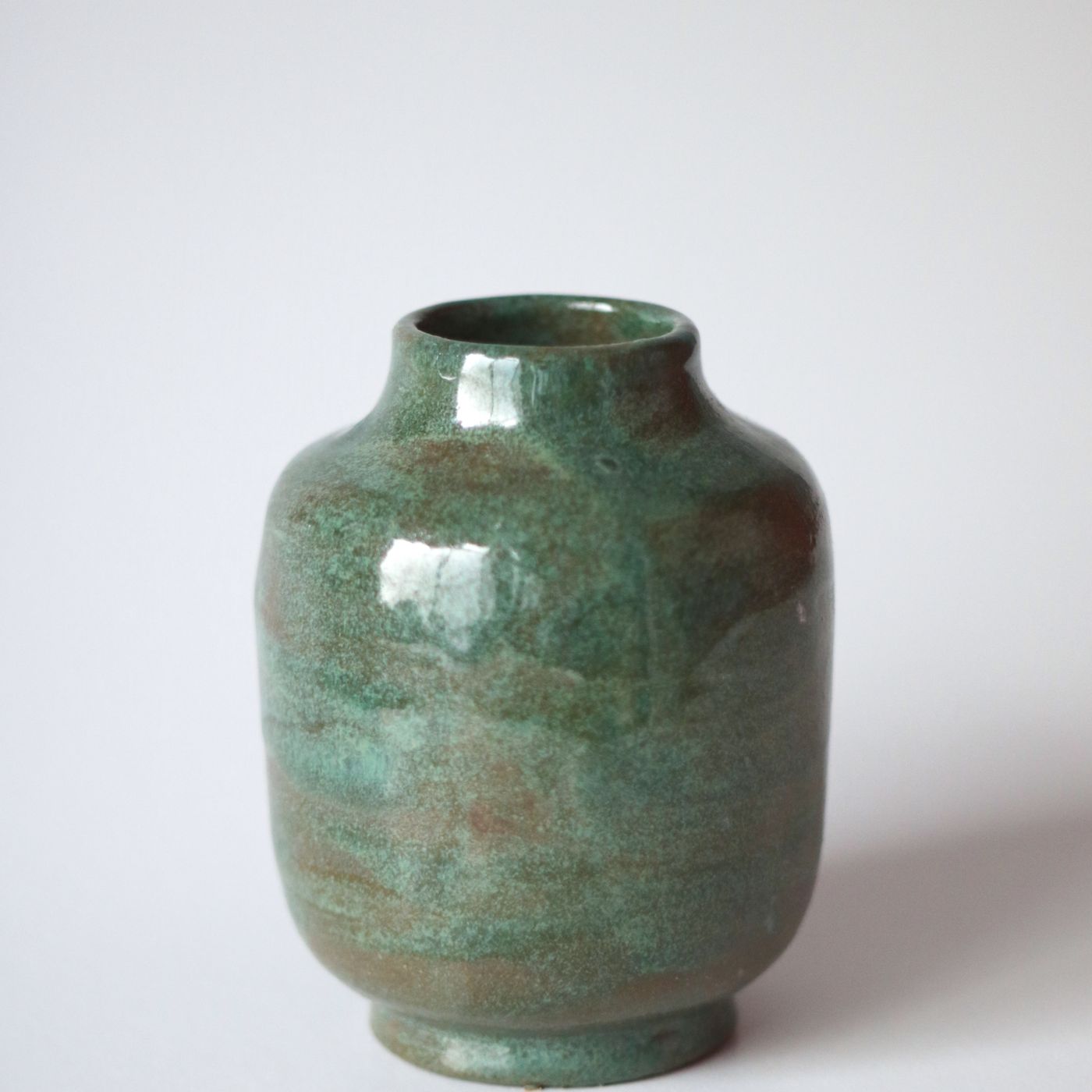 A beautifully made green ceramic vase, photographed against a plain white backdrop.