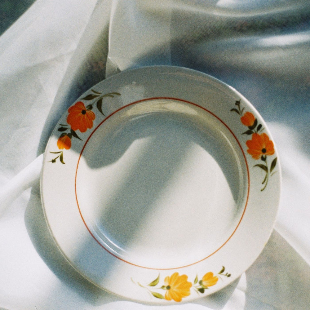 A floral porcelain plate, photographed from above on white fabric in soft light.