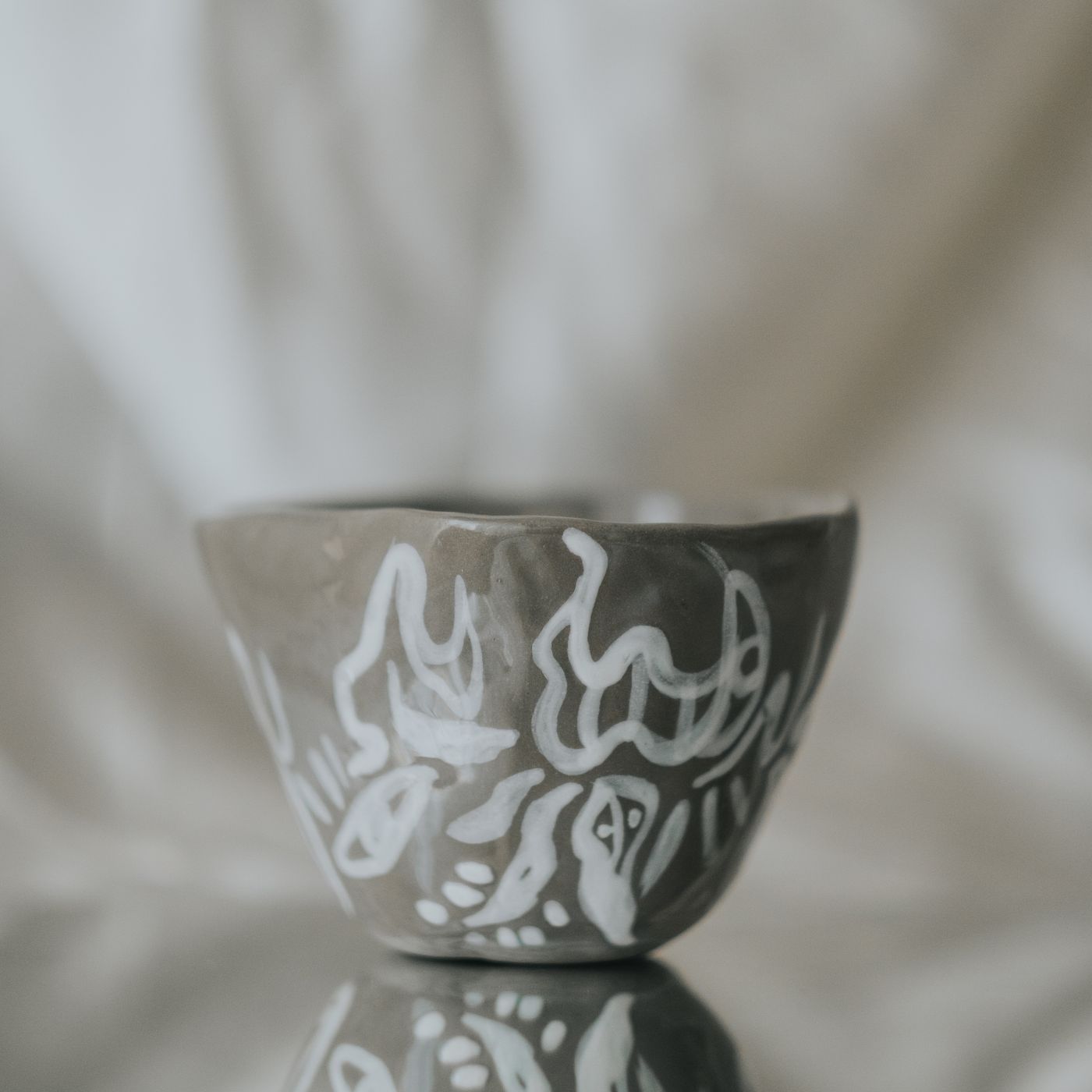 A handmade ceramic bowl decorated with artistic white patterns across its surface.