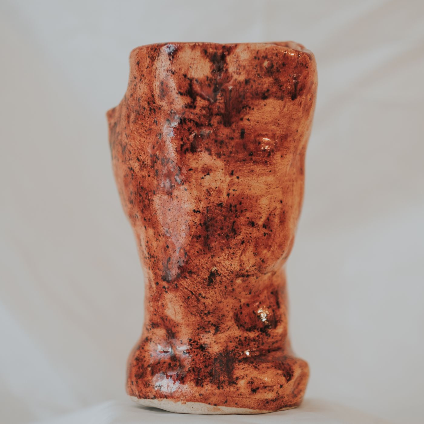 A handcrafted mug in earthy brown tones with a rustic, openly textured surface.