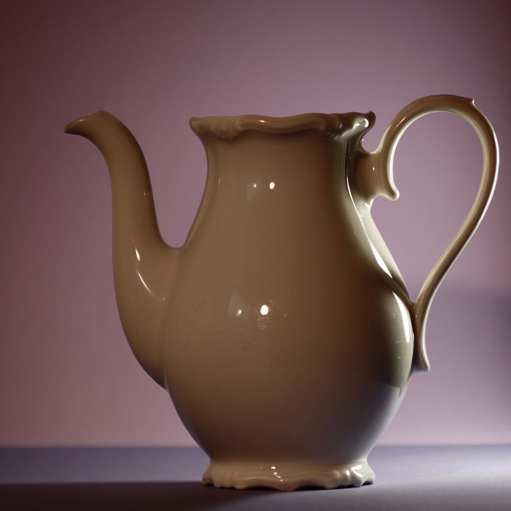 A classic porcelain teapot, photographed against a pastel background in gentle light.