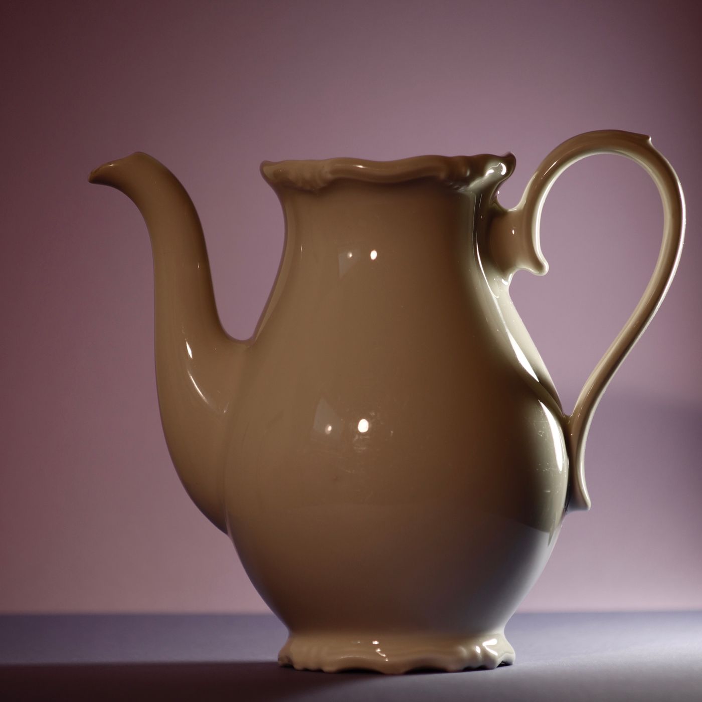 A classic porcelain teapot, photographed against a pastel background in gentle light.