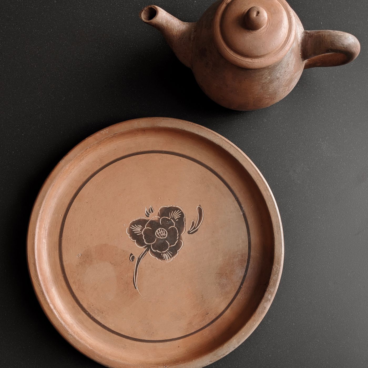 A vintage style earthenware teapot supplied with its matching decorative plate.