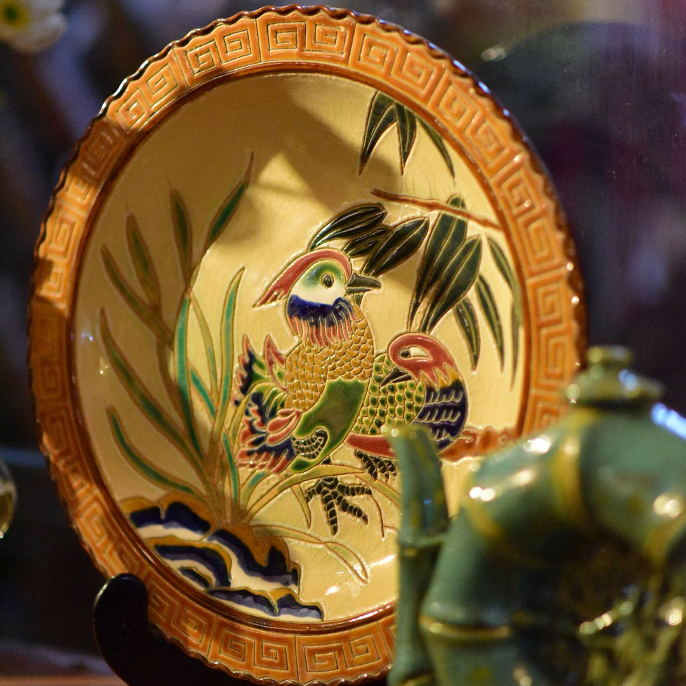 A vibrant ceramic plate built around a single bird motif, made for decor or for display.