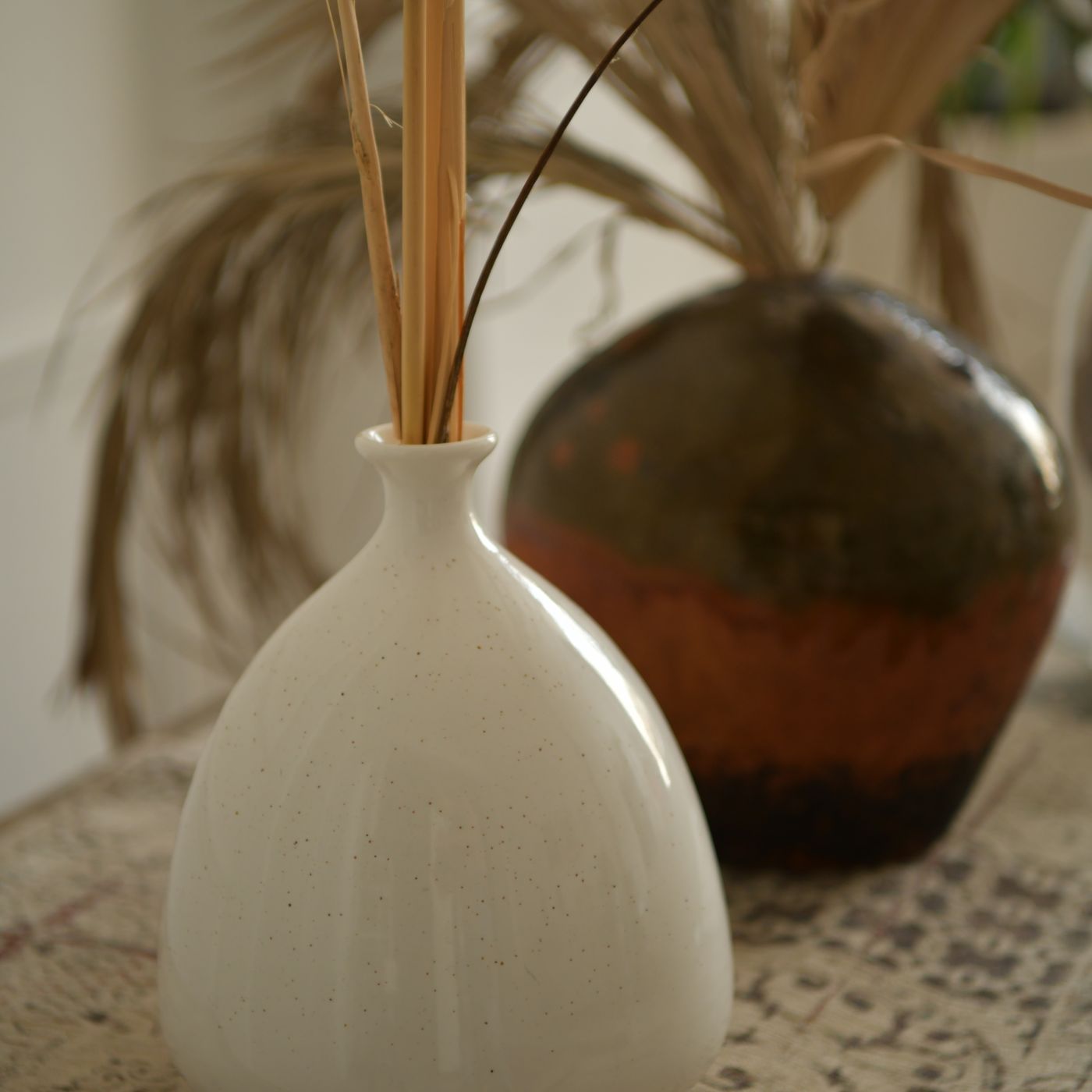 A minimalist ceramic vase, photographed holding a spray of dried pampas grass.