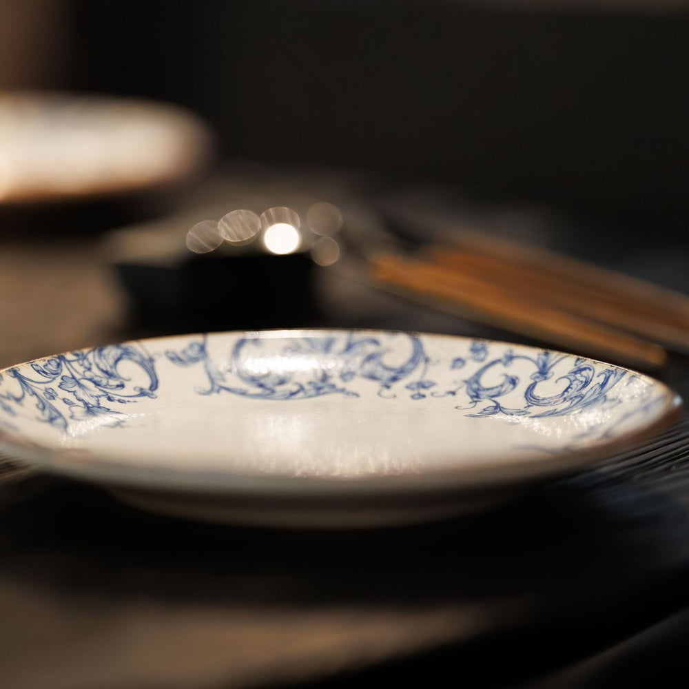 A blue and white ceramic plate, photographed on a rustic table with wooden cutlery laid across it.
