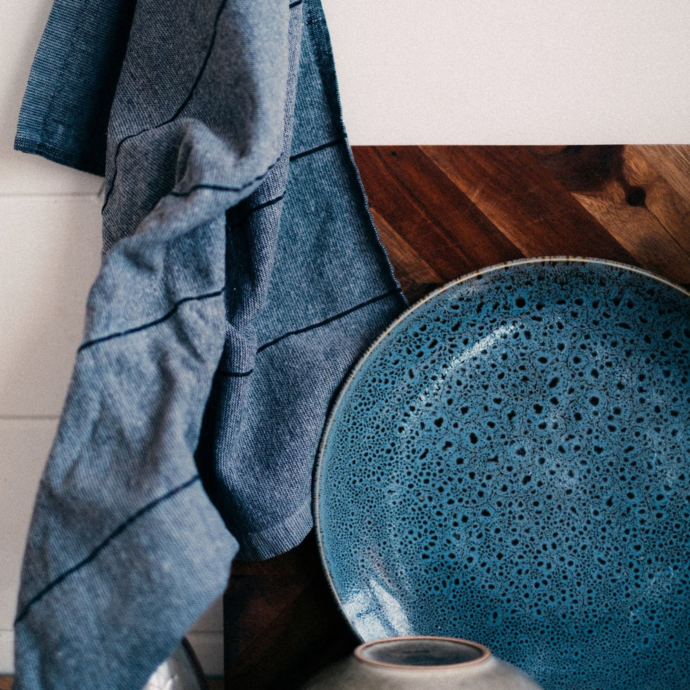 A textured blue plate, styled with a kitchen towel hanging behind it.