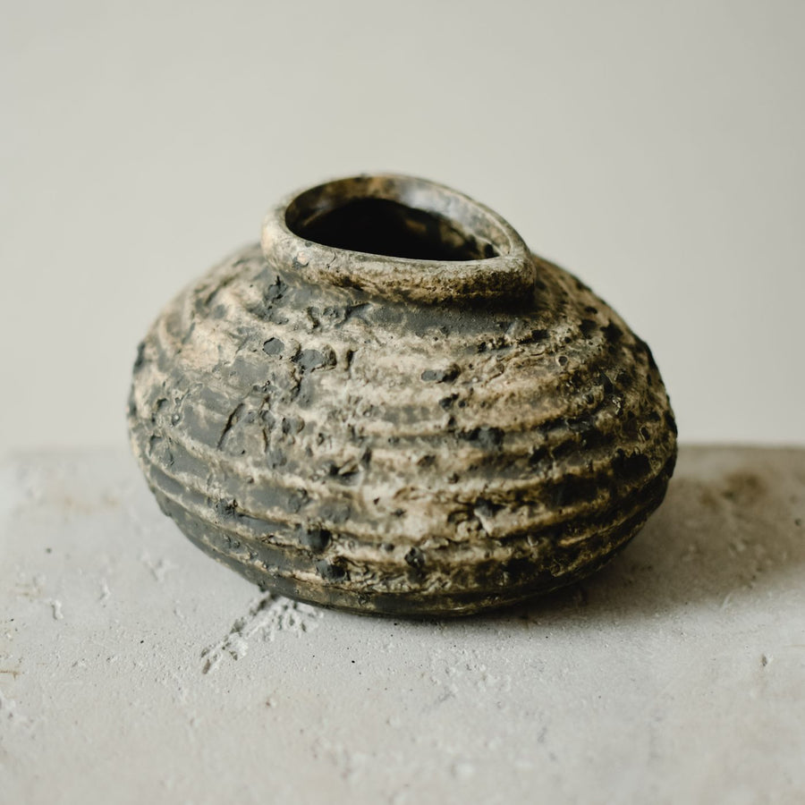 A rustic textured jar in a pared back japandi style, shown close up.