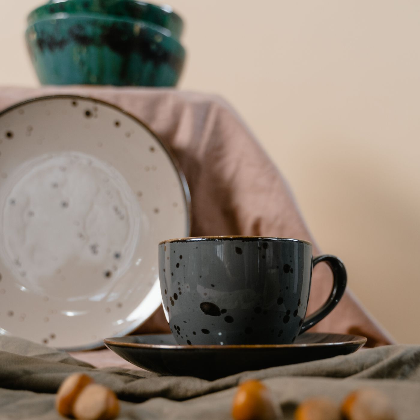 A plain ceramic cup and saucer photographed in a minimalist setting under soft light.